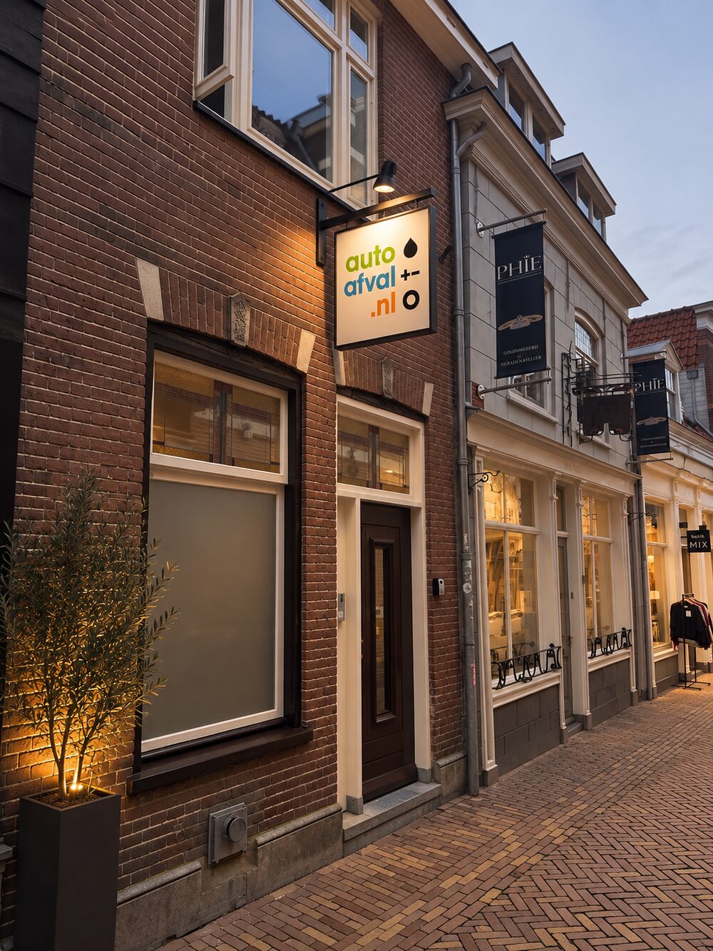Het pand van autoafval.nl aan de Hekelstraat in Alkmaar, met verlicht uithangbord naast de voordeur.